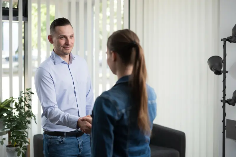 Michael Cernak begrüßt eine Bewerberin per Handschlag im ElevateJobs-Büro in Linz